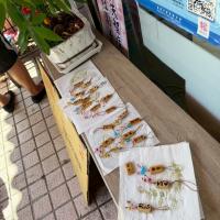 Bamboo strips with names written on them are sprayed with clear varnish and left to dry.