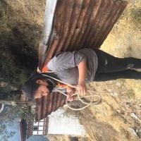 Carrying of roof sheet on her back downhill.