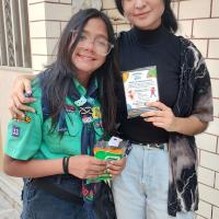 Scout posando junto a una chica con un folleto de promoción del proyecto