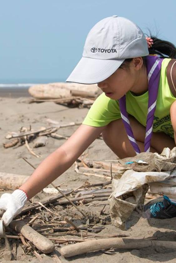 scout picking garbage from the beach