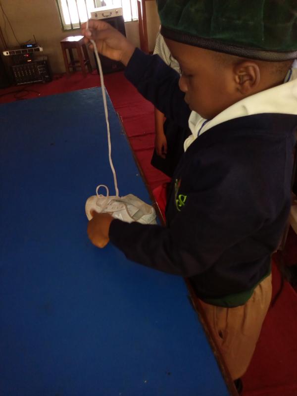 Cub scouts learning how to lace their shoe 