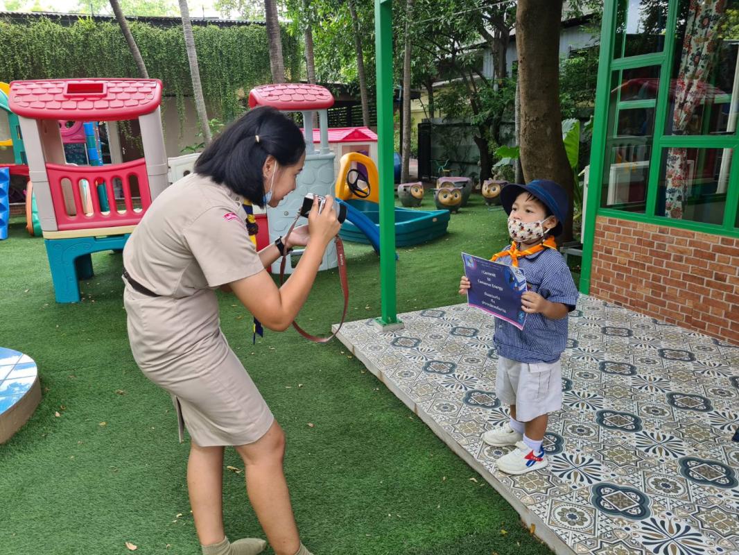 จิตอาสาถ่ายภาพถือป้ายคำมั่นสัญญาให้กับนักเรียน