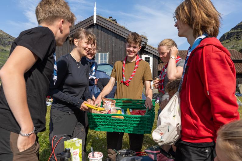 Young scouts collecting food items in a basket 