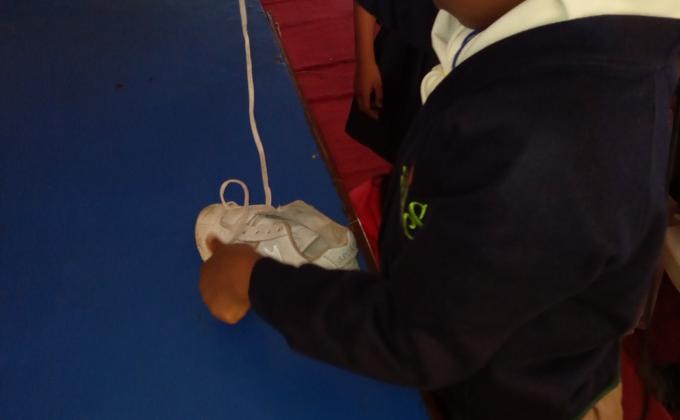 Cub scouts learning how to lace their shoe 