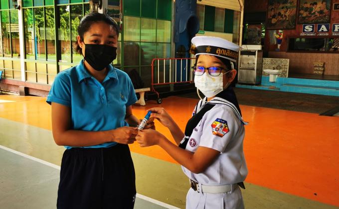 จิตอาสาแจกสเปรย์ แอลกอฮอล์สำหรับผู้ปกครองที่เข้ามาติดต่อภายในโรงเรียน